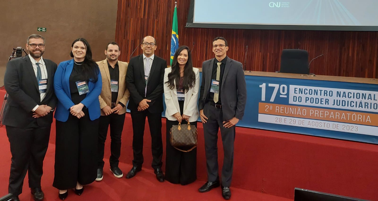 foto colorida dos O juiz de direito, Rodrigo Delgado, o Secretário Geral, Henrique Tavares, e os servidores Arthur Azevedo, Ariane Farias, Moisés Natan e Luciana Menezes de Medeiros, pousando para foto