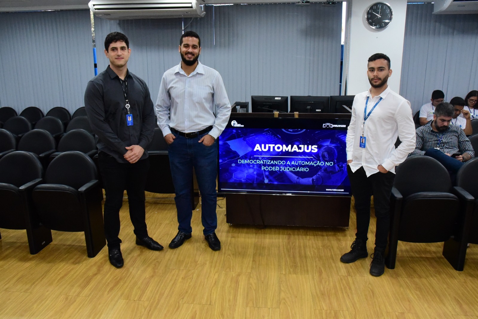 oto colorida com três servidores homens ao lado do banner na TV do automajus