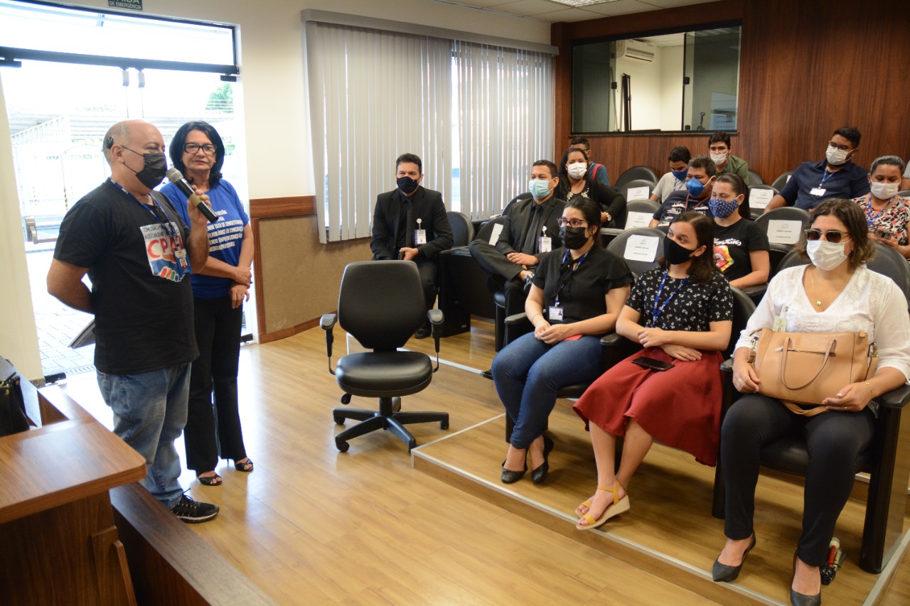 foto colorida na area interna de um auditoria que possuem gente sentada nas cadeiras e afrente há um colaborador do TJRR falando ao microfone