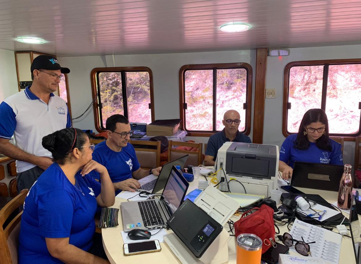 foto colorida com os servidores da vara da justiça itinerante reunidos em uma mesa trabalhando 