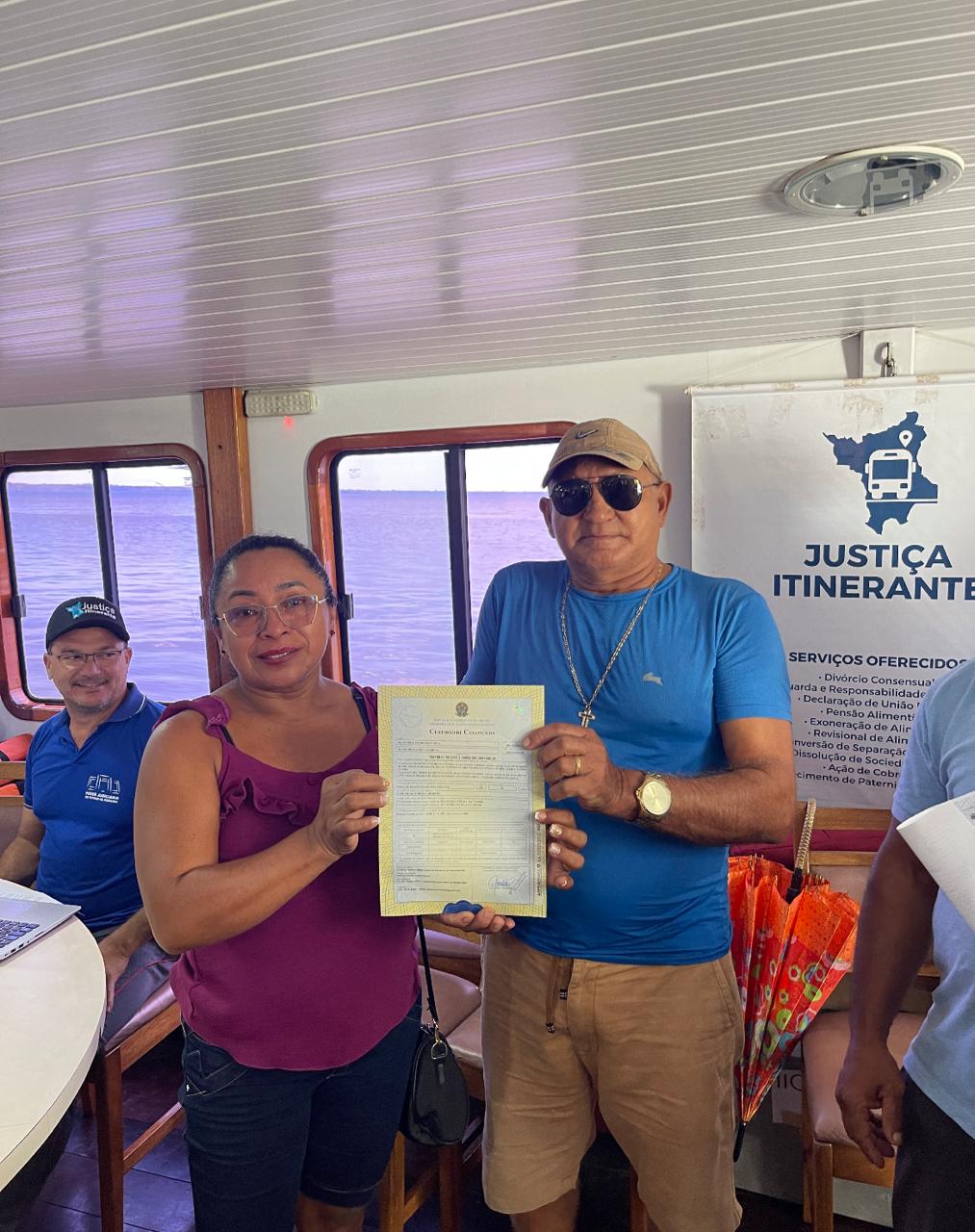 foto colorida de um homem e uma mulher segurando uma certidão 