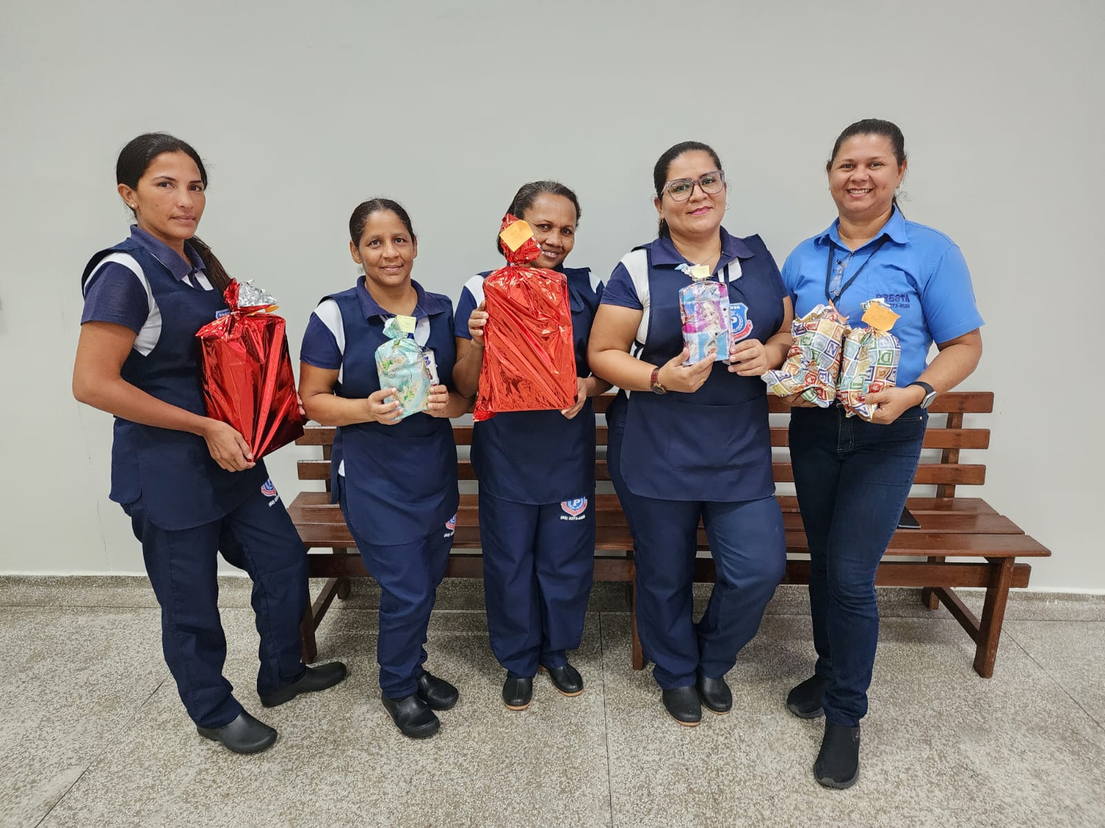 foto colorida de cinco servidoras terceirizadas pousando para a foto e segurando presentes