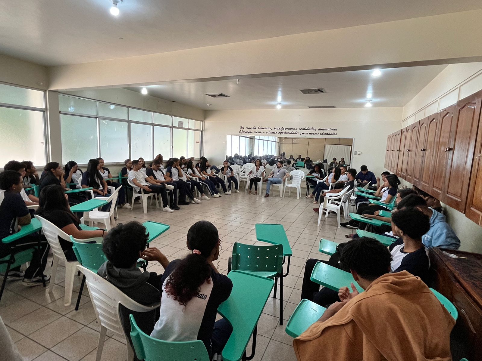 Alunos sentados conversando em uma uma roda de cadeiras.