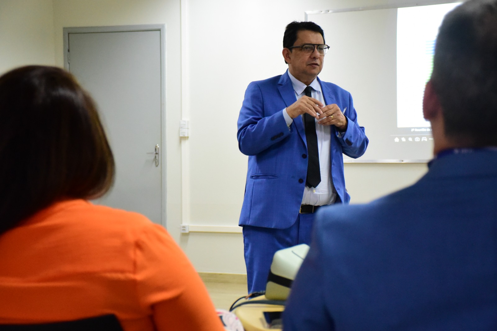 Imagem colorida mostra o presidente do Tribunal de Justiça, desembargador Jésus Nascimento, em pé falando para as pessoas que estão sentadas. Atrás dele, há uma projeção de computador.