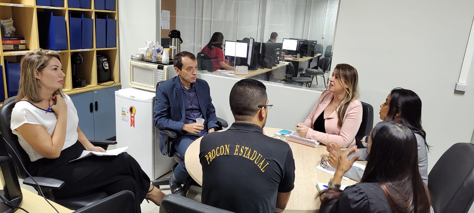 magem colorida mostra o desembargador Erick Linhares, Ouvidor-Geral do TJRR, durante reunião com o Procon Estadual. Na reunião contém mais 05 pessoas sentadas, sendo uma delas trajando uma camisa com  a frase “Procon Estadual” de frente para o desembargador.