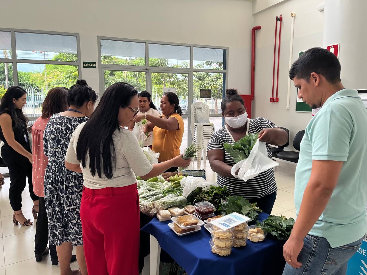 foto colorida de servidores comprando legumes na feirinha organica