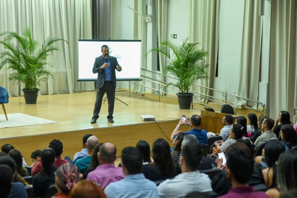 foto colorida tirada palestrante falando ao microfone no palco do auditório 