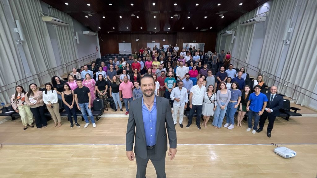 foto colorida na area interna do auditorio do Forum Civel, onde todos estão em pé e o Palestrante olhando para a fotografia