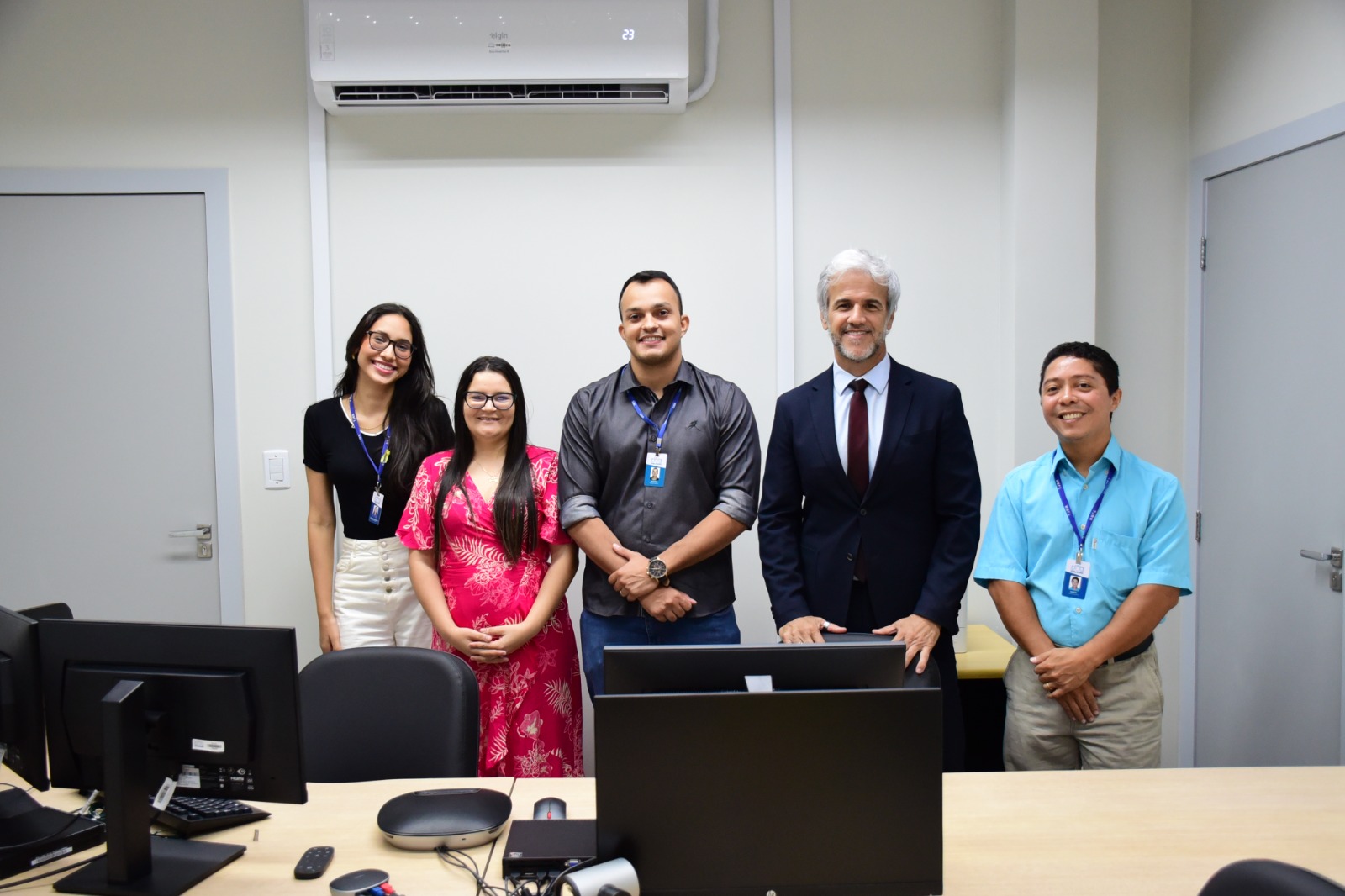 foto colorida de servidores pousando para fotografia dentro da sala nova