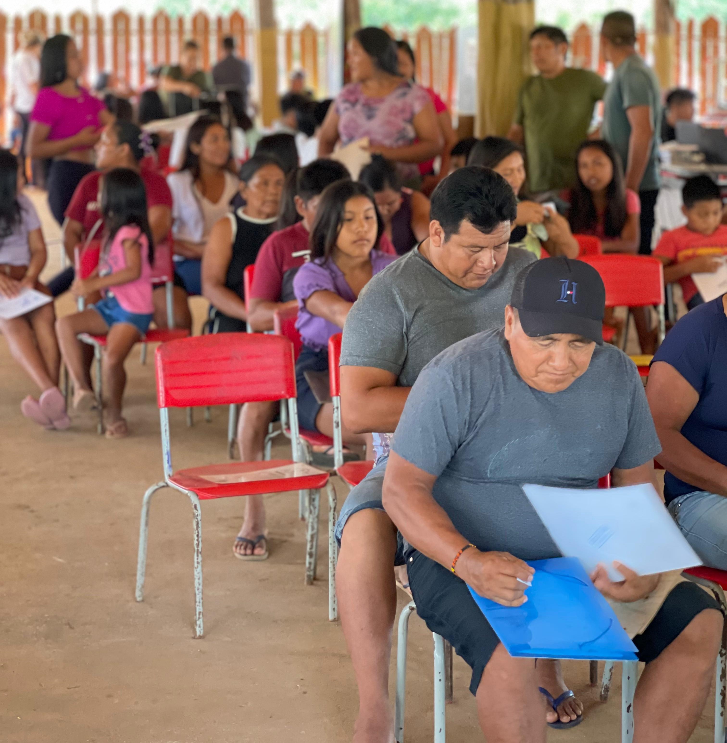 Imagem colorida mostra um grupo de pessoas sentadas durante ação do Justiça Itinerante no interior do Estado.