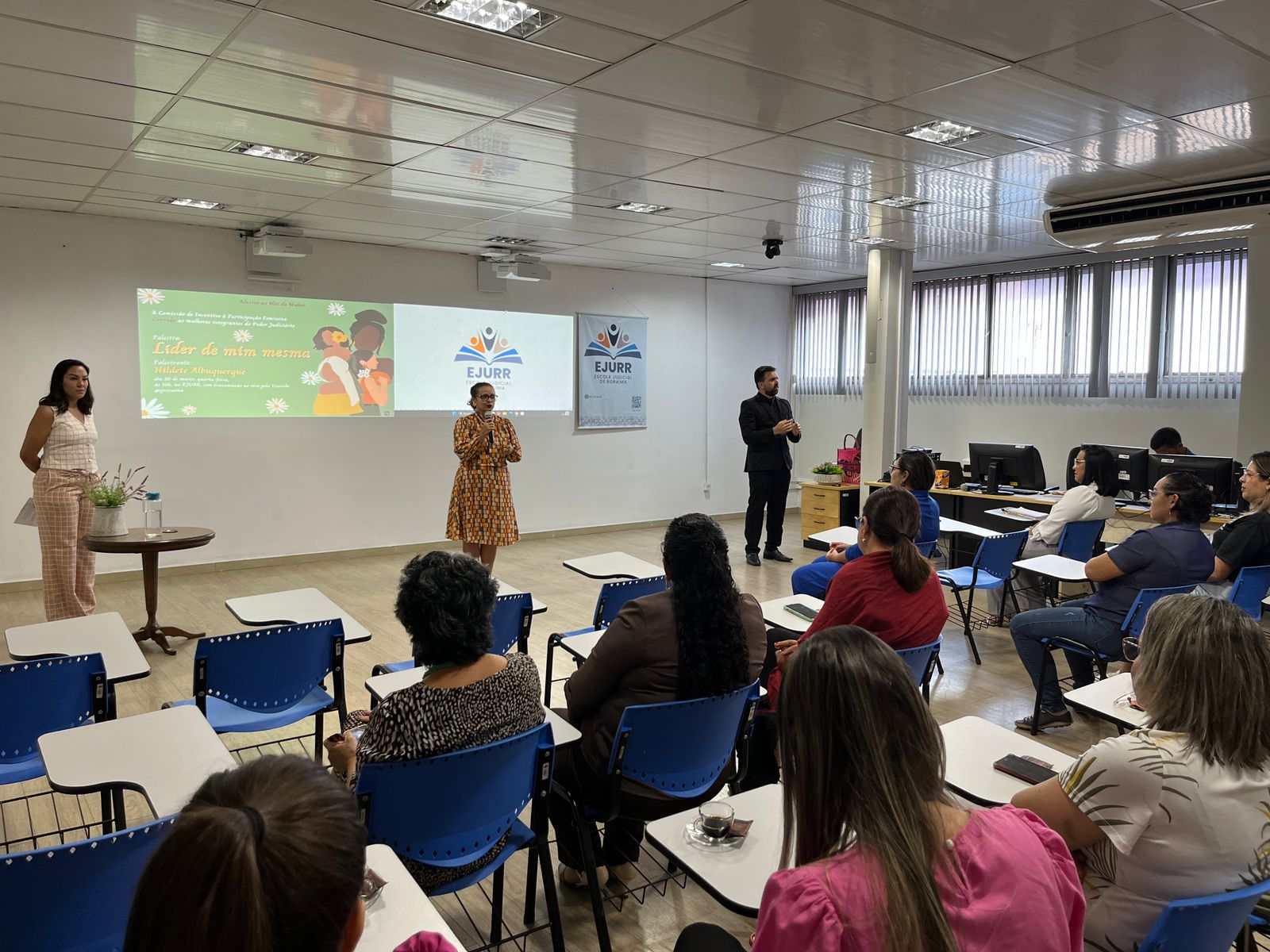 Foto colorida de diversas mulheres reunidas em  uma sala. 