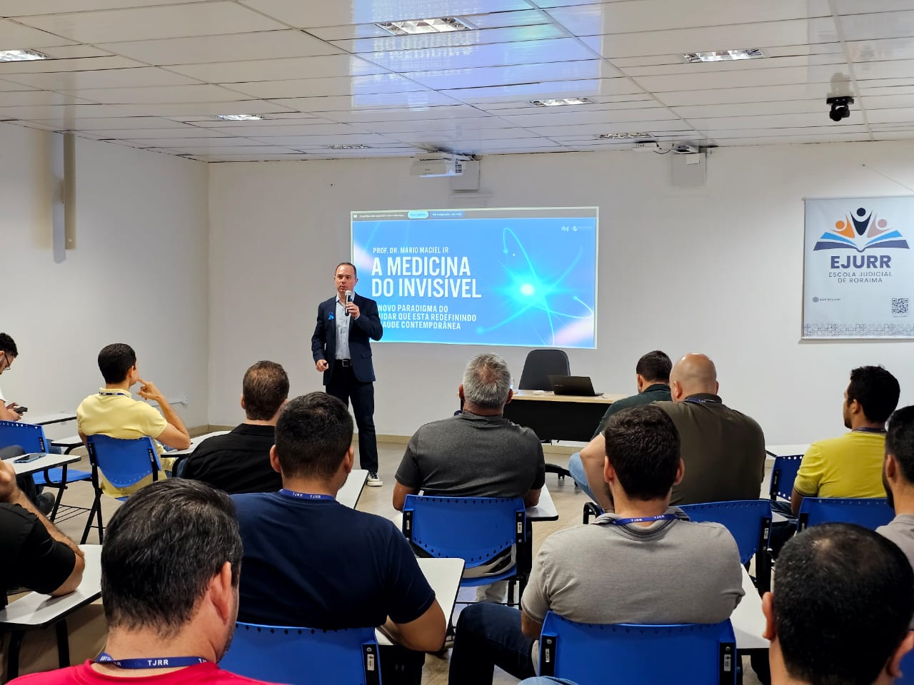Foto colorida mostrando um público, majoritariamente masculino, sentados em fileiras para assistir a palestra. Mais a frente deles um outro homens está discursando. Abaixo a frase "Informar para Prevenir -  Palestra sobre saúde do homem em alusão ao Novembro Azul é realizada no TJRR"
