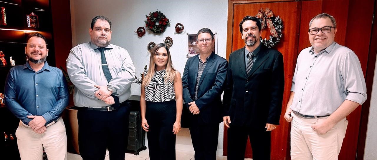 Foto colorida mostra seis pessoas em pé posando para a foto. Uma delas é mulher