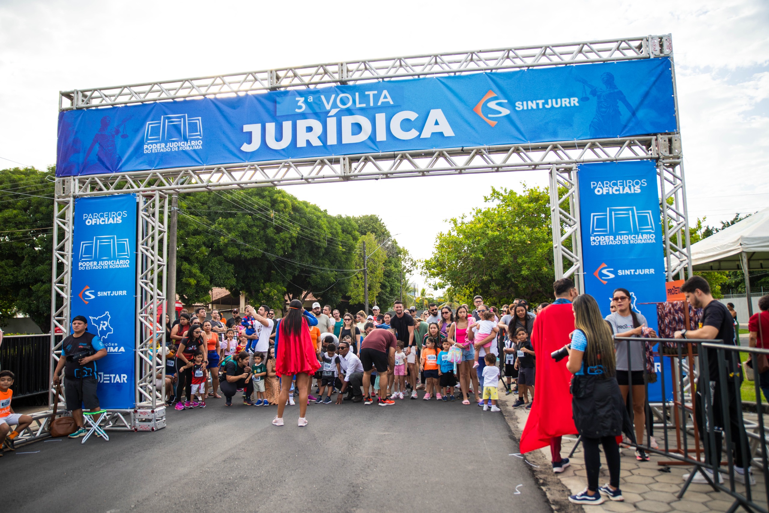  foto colorida da largada em ambiente externo arborizado. Abaixo da largada estão várias crianças posicionadas. 