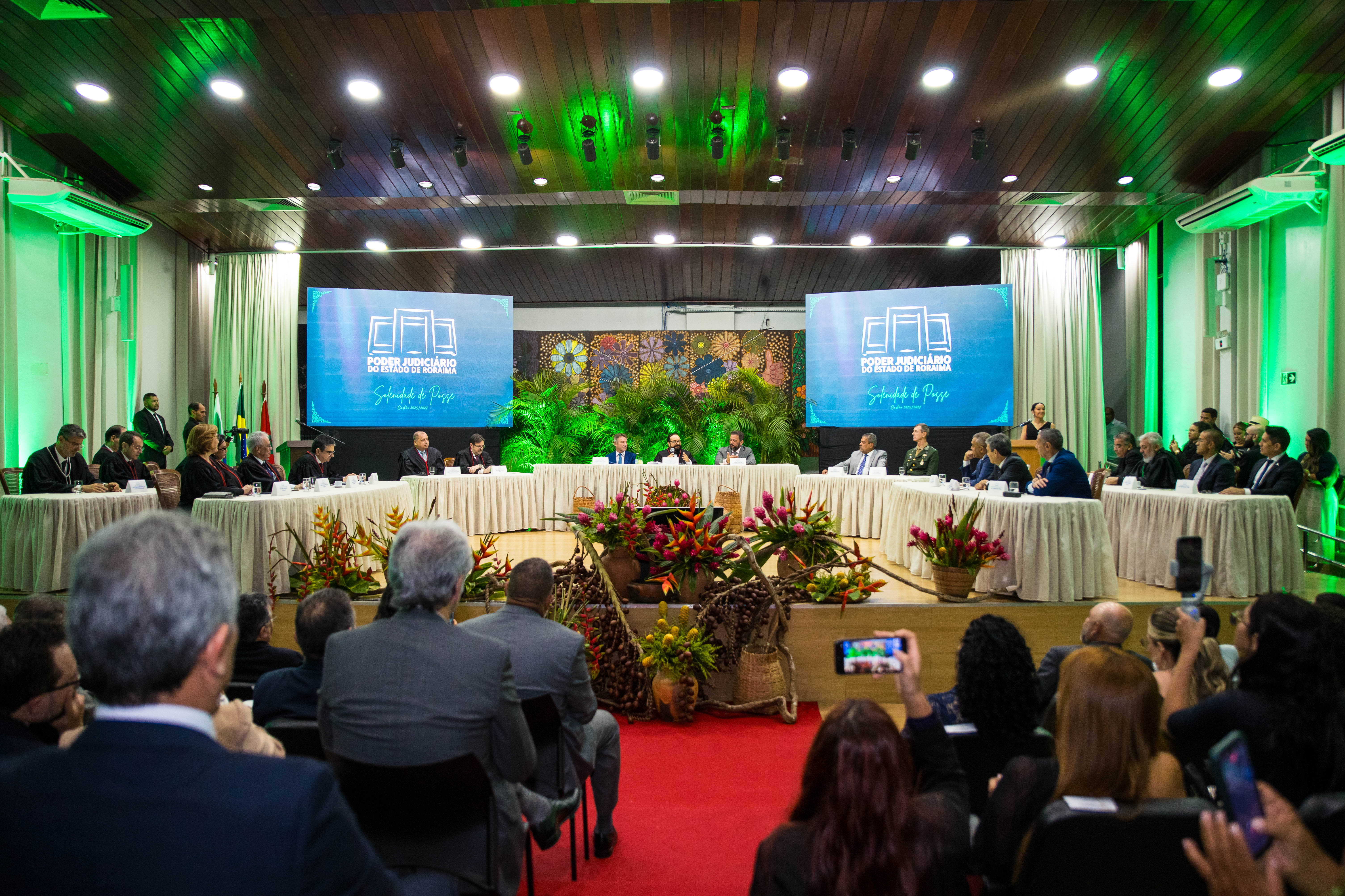 Foto colorida mostrando o auditório do Fórum Cível cheio de pessoas durante a cerimonia de posse. No centro o des. Leonardo Cupello está sentado discursando 