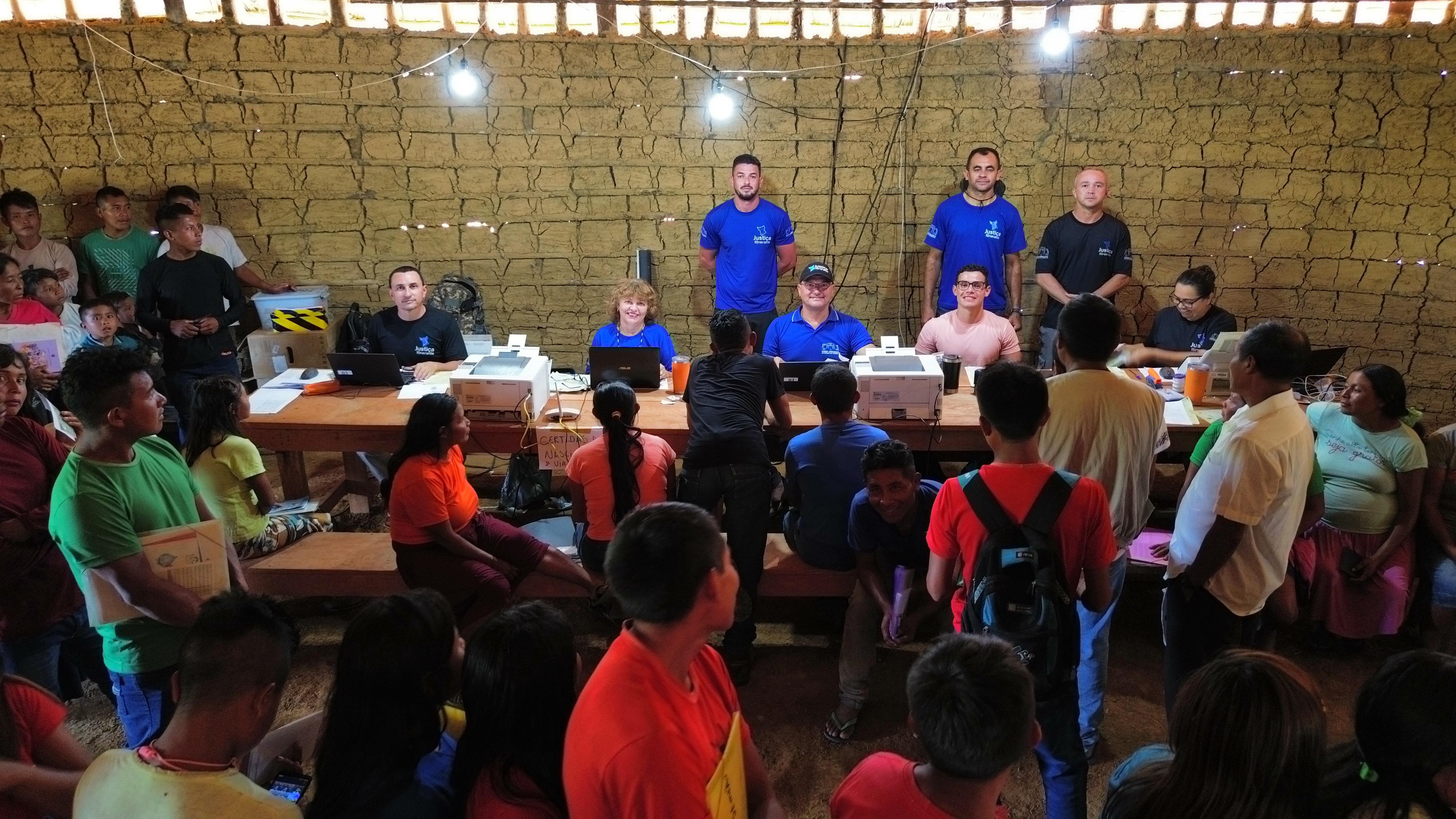 Imagem colorida mostrando pessoas sentadas esperando atendimento da Justiça Itinerante