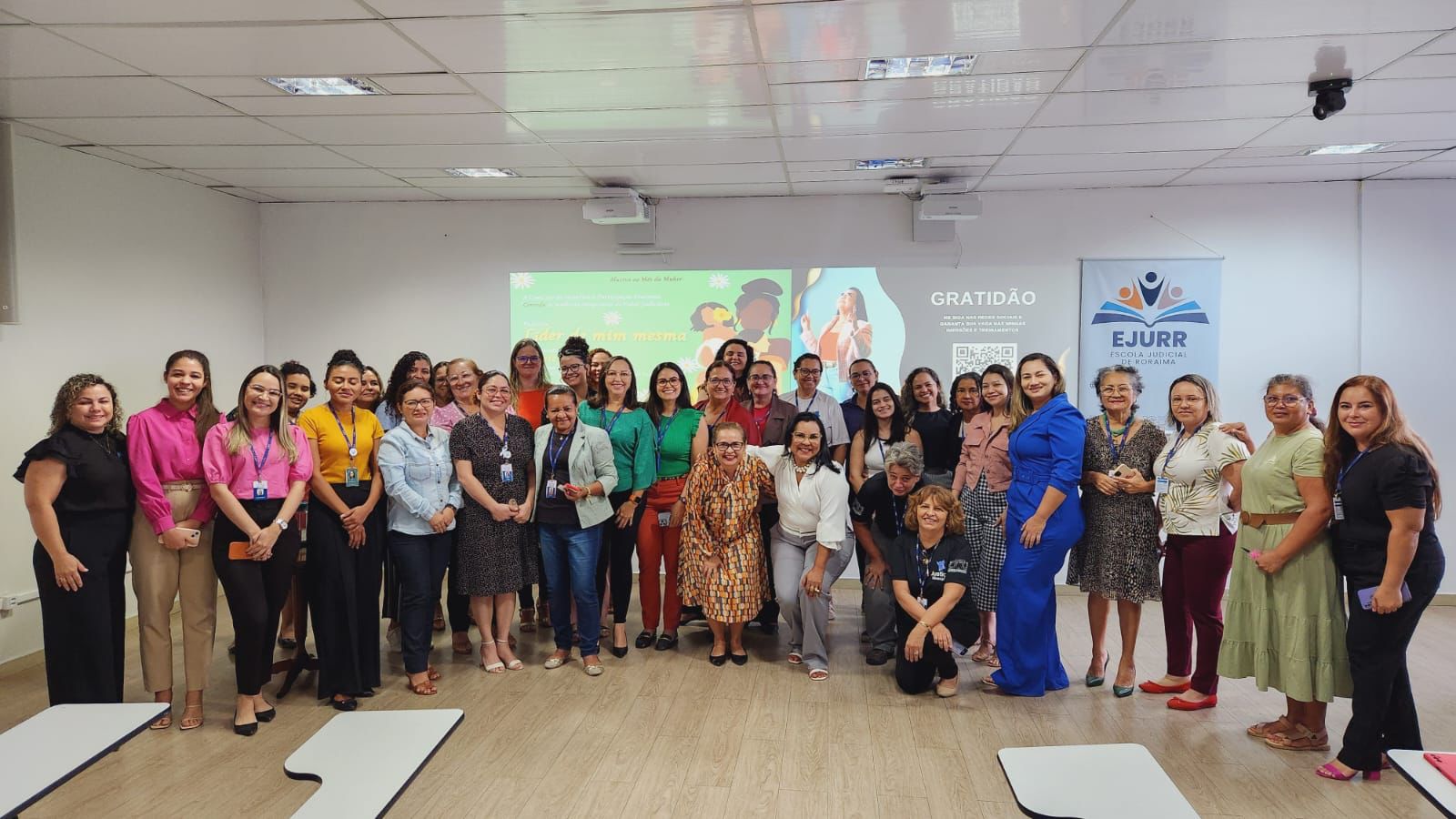 A imagem mostra um grande grupo de mulheres posando para uma foto em uma sala bem iluminada. A maioria das mulheres está em pé, dispostas em várias fileiras, enquanto algumas estão agachadas na frente para garantir que todos apareçam na foto. A imagem mostra um grande grupo de mulheres posando para uma foto em uma sala bem iluminada. A maioria das mulheres está em pé, dispostas em várias fileiras, enquanto algumas estão agachadas na frente para garantir que todos apareçam na foto.