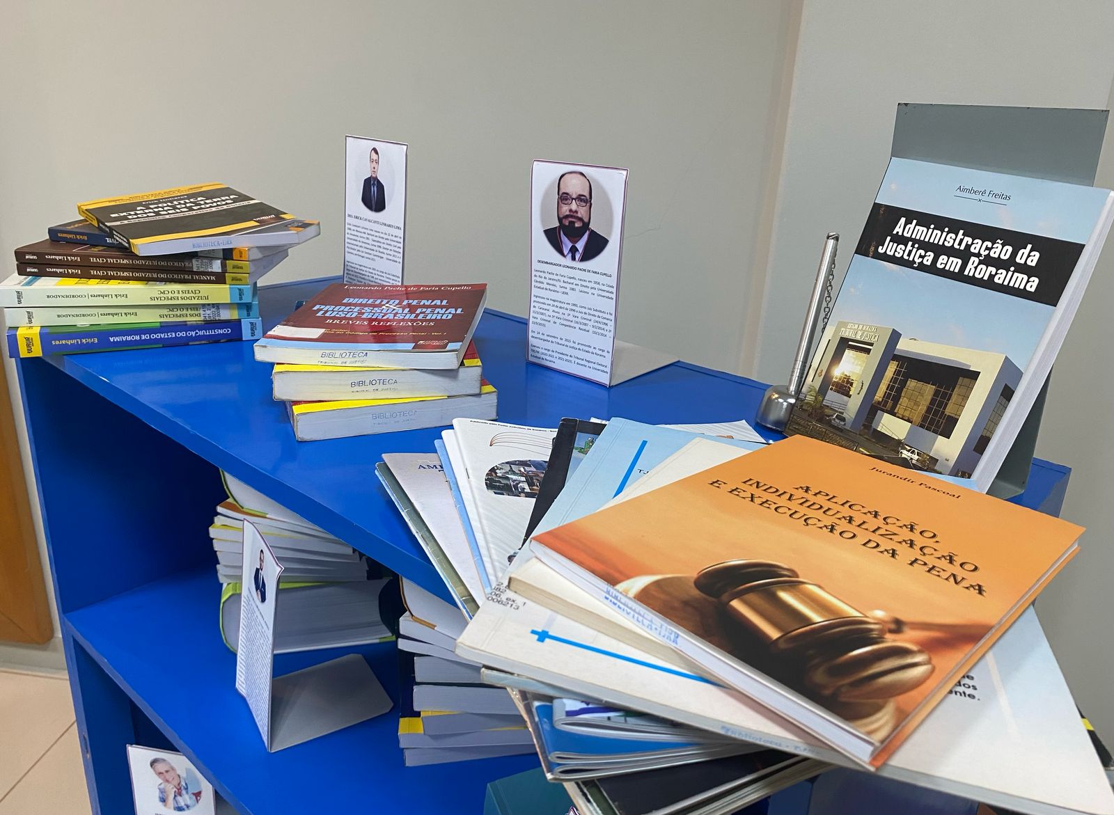 Foto colorida de livros acima de uma bancada azul. Foto colorida de livros acima de uma bancada azul.