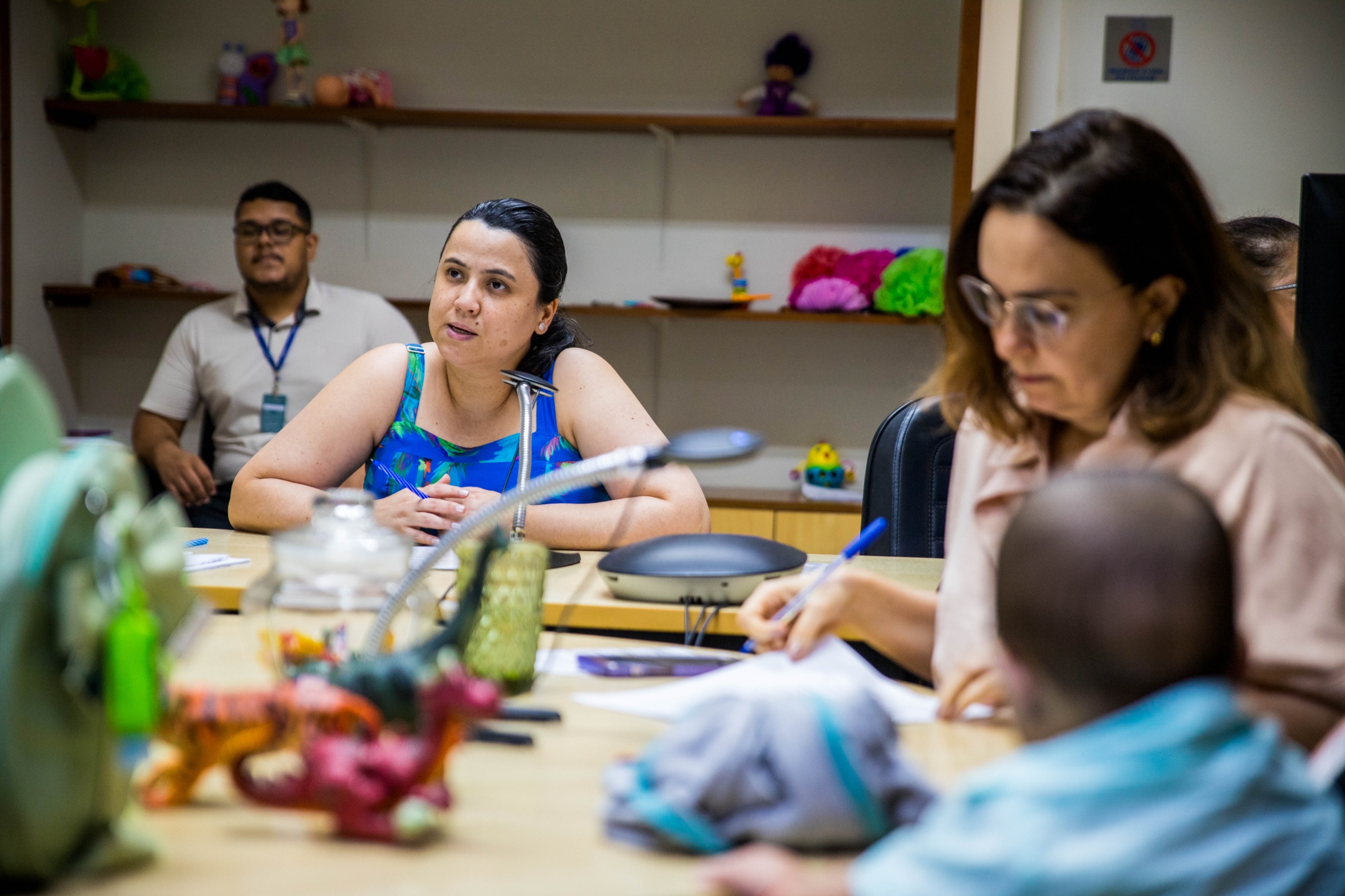 foto colorida de uma sala de reunião da Juíza Titular da 2ª Vara de Família e Sucessões, Joana Sarmento, ao fundo e em primeiro plano está um bebe de costa com a imagem desfocada junto a uma mulher foto colorida de uma sala de reunião da Juíza Titular da 2ª Vara de Família e Sucessões, Joana Sarmento, ao fundo e em primeiro plano está um bebe de costa com a imagem desfocada junto a uma mulher