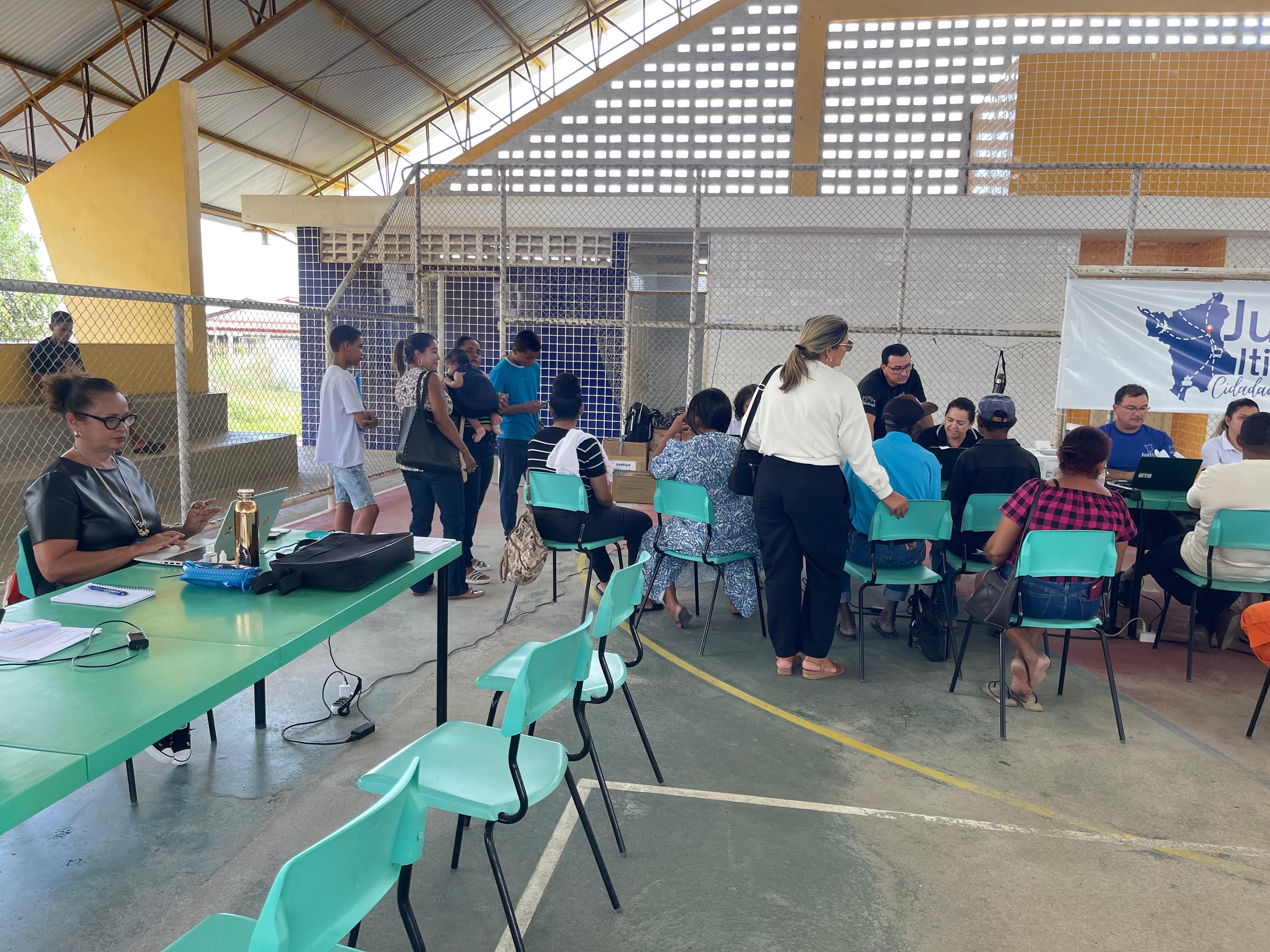 Foto colorida contém a Juíza Titular da Vara da Justiça Itinerante do TJRR, Graciete Sotto Mayor Ribeiro, utilizando notbook, durante ação da Justiça Itinerante em um quadra de escola, no município de Iracema. No segundo plano da imagem logo ao lado da juíza, estão servidores da Vara da Justiça Itinerante atendendo os munícipes que se encontram sentados à frente dos servidores. Foto colorida contém a Juíza Titular da Vara da Justiça Itinerante do TJRR, Graciete Sotto Mayor Ribeiro, utilizando notbook, durante ação da Justiça Itinerante em um quadra de escola, no município de Iracema. No segundo plano da imagem logo ao lado da juíza, estão servidores da Vara da Justiça Itinerante atendendo os munícipes que se encontram sentados à frente dos servidores.
