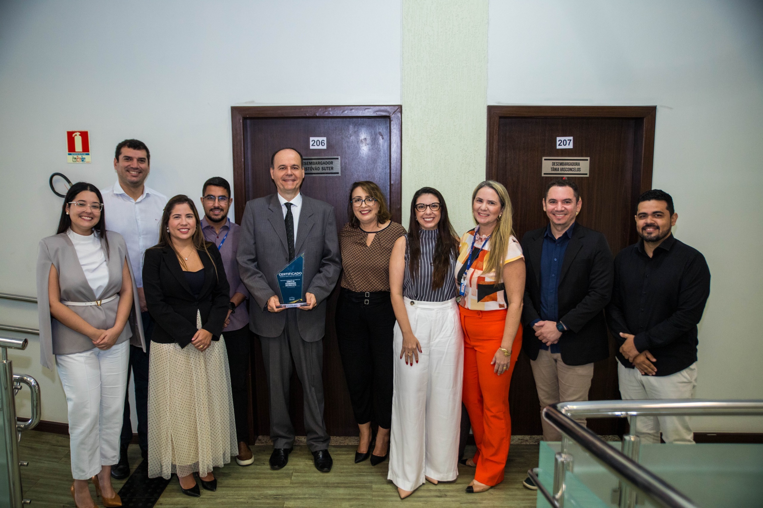 Imagem colorida contém Desembargador Cristóvão Suter,segurando placa de premiação da certificação do ISO 9001, e posando para fotografia ao lado da Juíza Auxiliar da Presidência do TJRR, Lana Leitão, da Subsecretária de Processos e Gestão da Qualidade, Erika Horta e mais sete servidores do TJRR, em frente a entrada gabinete do Desembargador Cristóvão, localizado no Palácio da Justiça. Imagem colorida contém Desembargador Cristóvão Suter,segurando placa de premiação da certificação do ISO 9001, e posando para fotografia ao lado da Juíza Auxiliar da Presidência do TJRR, Lana Leitão, da Subsecretária de Processos e Gestão da Qualidade, Erika Horta e mais sete servidores do TJRR, em frente a entrada gabinete do Desembargador Cristóvão, localizado no Palácio da Justiça.