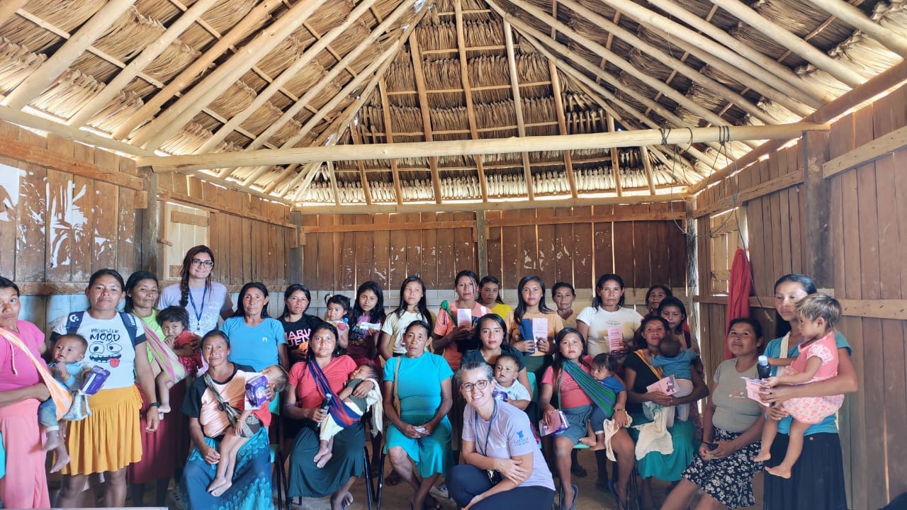 A imagem mostra um grupo numeroso de mulheres e crianças reunidas dentro de uma construção indígena A imagem mostra um grupo numeroso de mulheres e crianças reunidas dentro de uma construção indígena