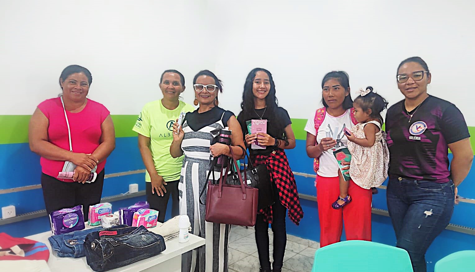 A imagem mostra um grupo de seis mulheres e uma criança em pé, posando para uma foto A imagem mostra um grupo de seis mulheres e uma criança em pé, posando para uma foto