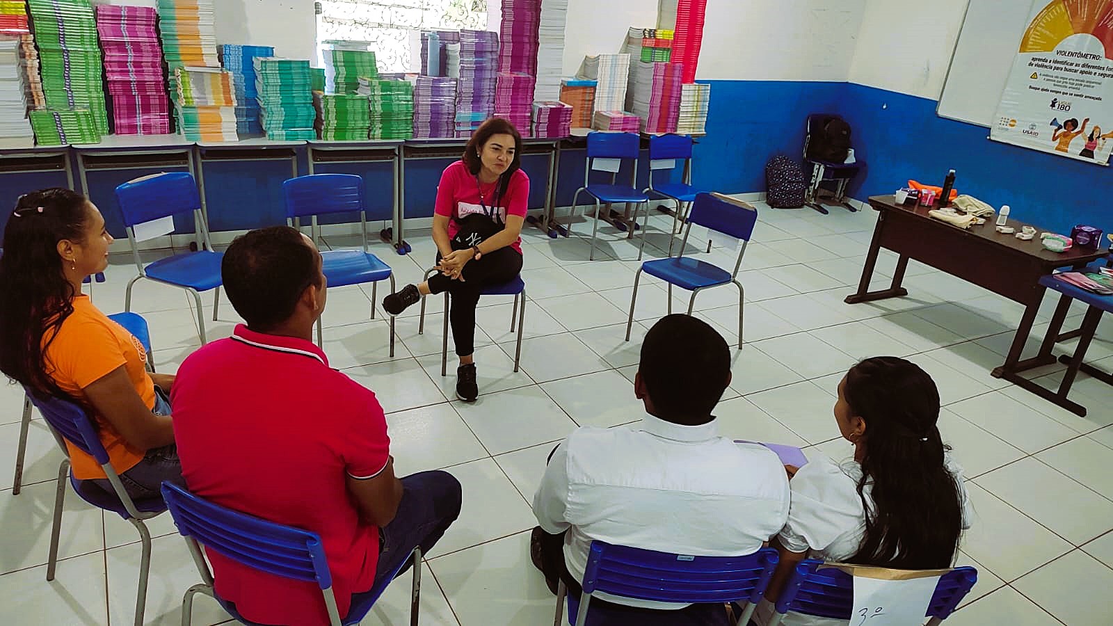 A imagem mostra um grupo de cinco pessoas reunidas em uma sala durante uma ação do programa caminhos seguros A imagem mostra um grupo de cinco pessoas reunidas em uma sala durante uma ação do programa caminhos seguros