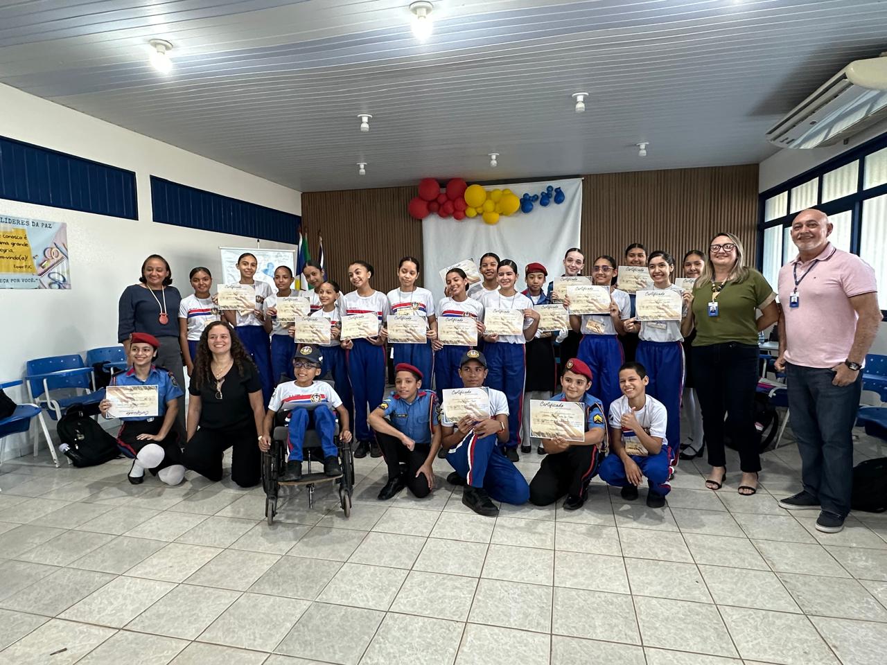 foto colorida dentro de uma sala de aula de uma turma de alunos líderes e servidores do TJRR pousando para fotografia mostrando os certificados. Há 19 deles em pé e 7 abaixados ao lado de um aluno cadeirante. Abaixo está o texto “ Diálogo e transformação - Justiça Comunitária realiza oficinas com alunos e servidores de colégio em Rorainópolis”. foto colorida dentro de uma sala de aula de uma turma de alunos líderes e servidores do TJRR pousando para fotografia mostrando os certificados. Há 19 deles em pé e 7 abaixados ao lado de um aluno cadeirante. Abaixo está o texto “ Diálogo e transformação - Justiça Comunitária realiza oficinas com alunos e servidores de colégio em Rorainópolis”.