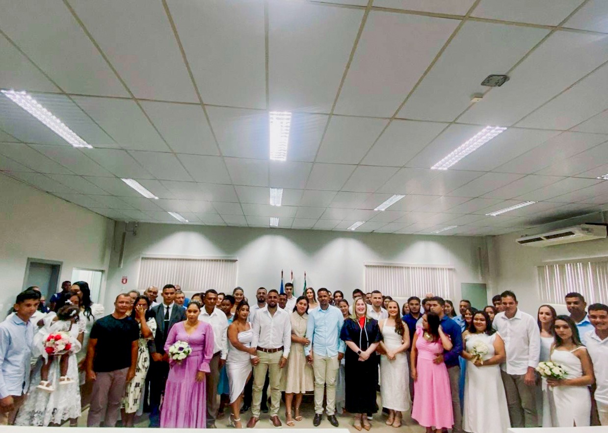 Foto colorida dos trinta casais pousando para fotografia dentro do auditório do Fórum Juiz Umberto Teixeira.