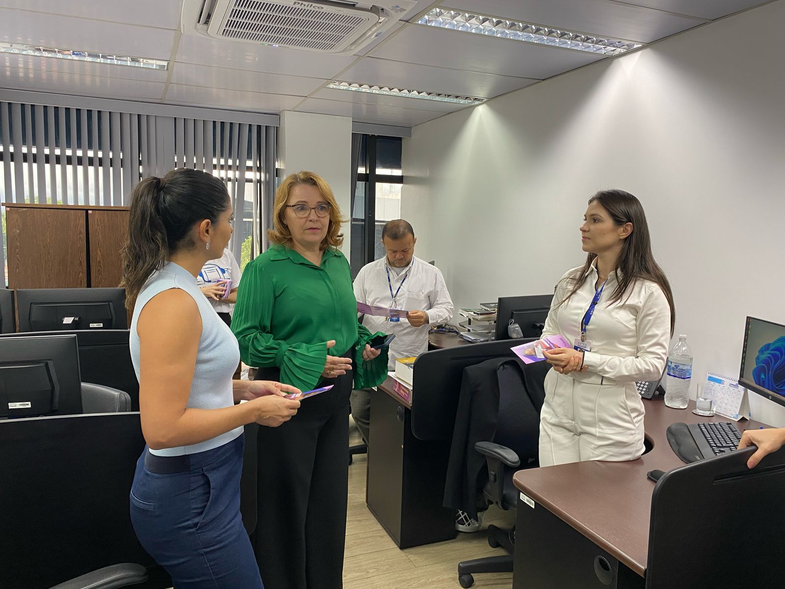 A imagem colorida mostra três mulheres estão interagindo em uma área interna. Ao centro da imagem a Desembargadora e Ouvidora Geral de Justiça, Elaine Bianchi. A imagem colorida mostra três mulheres estão interagindo em uma área interna. Ao centro da imagem a Desembargadora e Ouvidora Geral de Justiça, Elaine Bianchi.