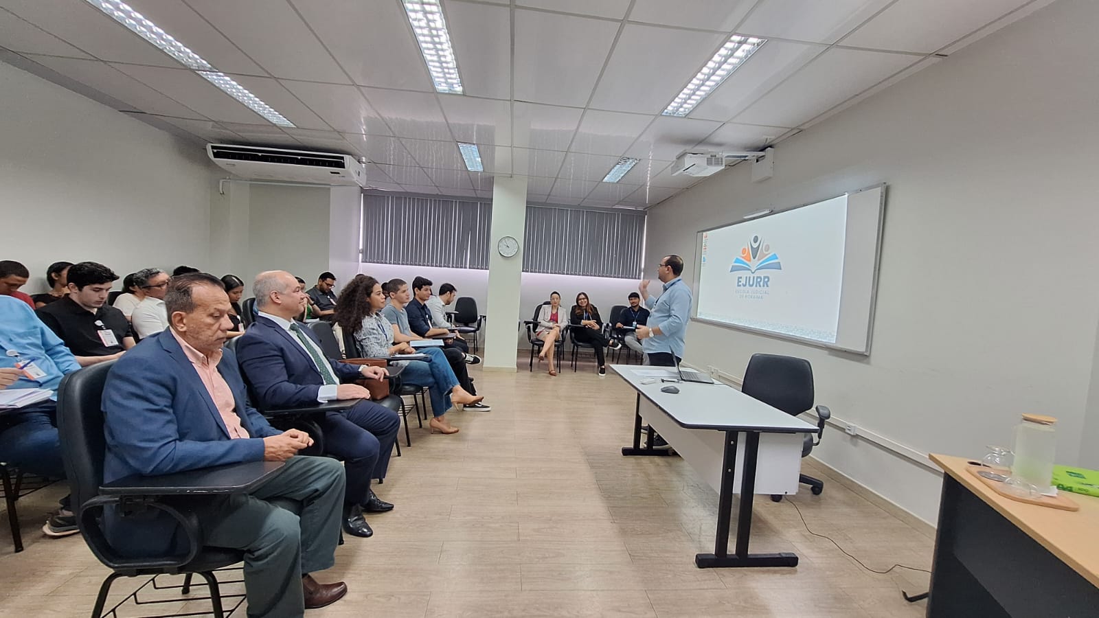 Imagem colorida de uma servidora do TJ falando para o grupo de estudantes.