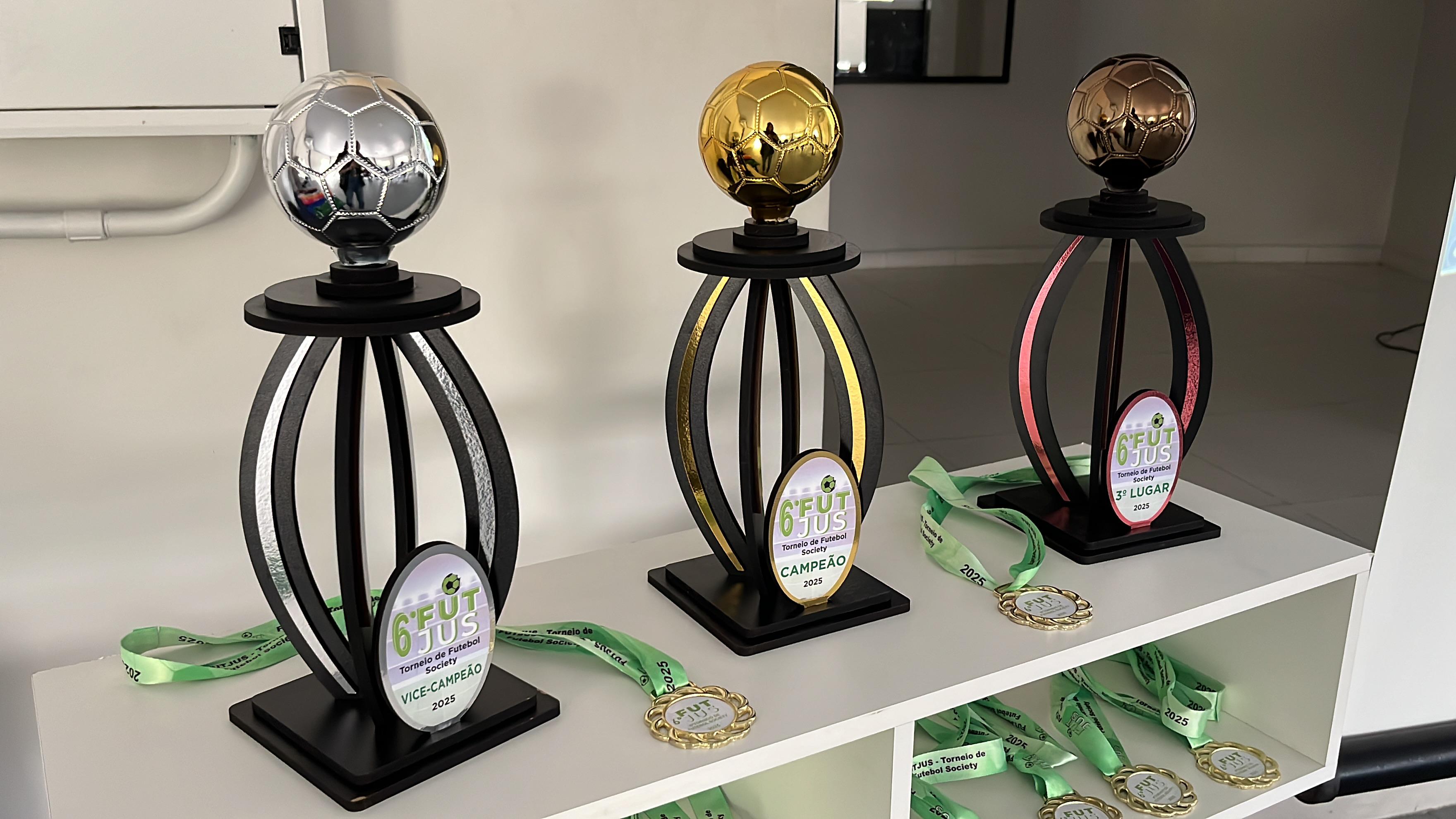 : imagem colorida de três troféis e algumas medalhas acima de uma bancada branca : imagem colorida de três troféis e algumas medalhas acima de uma bancada branca