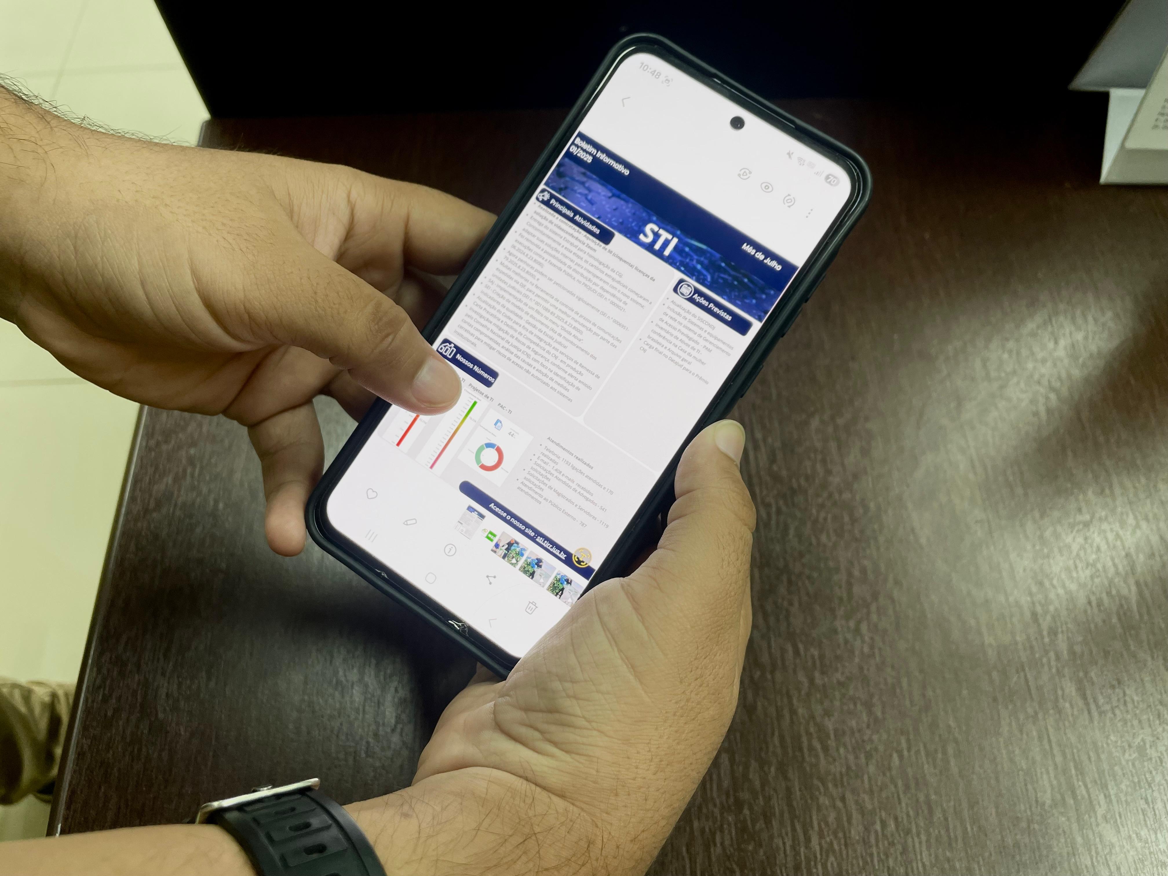 imagem colorida dando enfoque em uma pessoa segurando um celular que mostra o boletim informativo imagem colorida dando enfoque em uma pessoa segurando um celular que mostra o boletim informativo