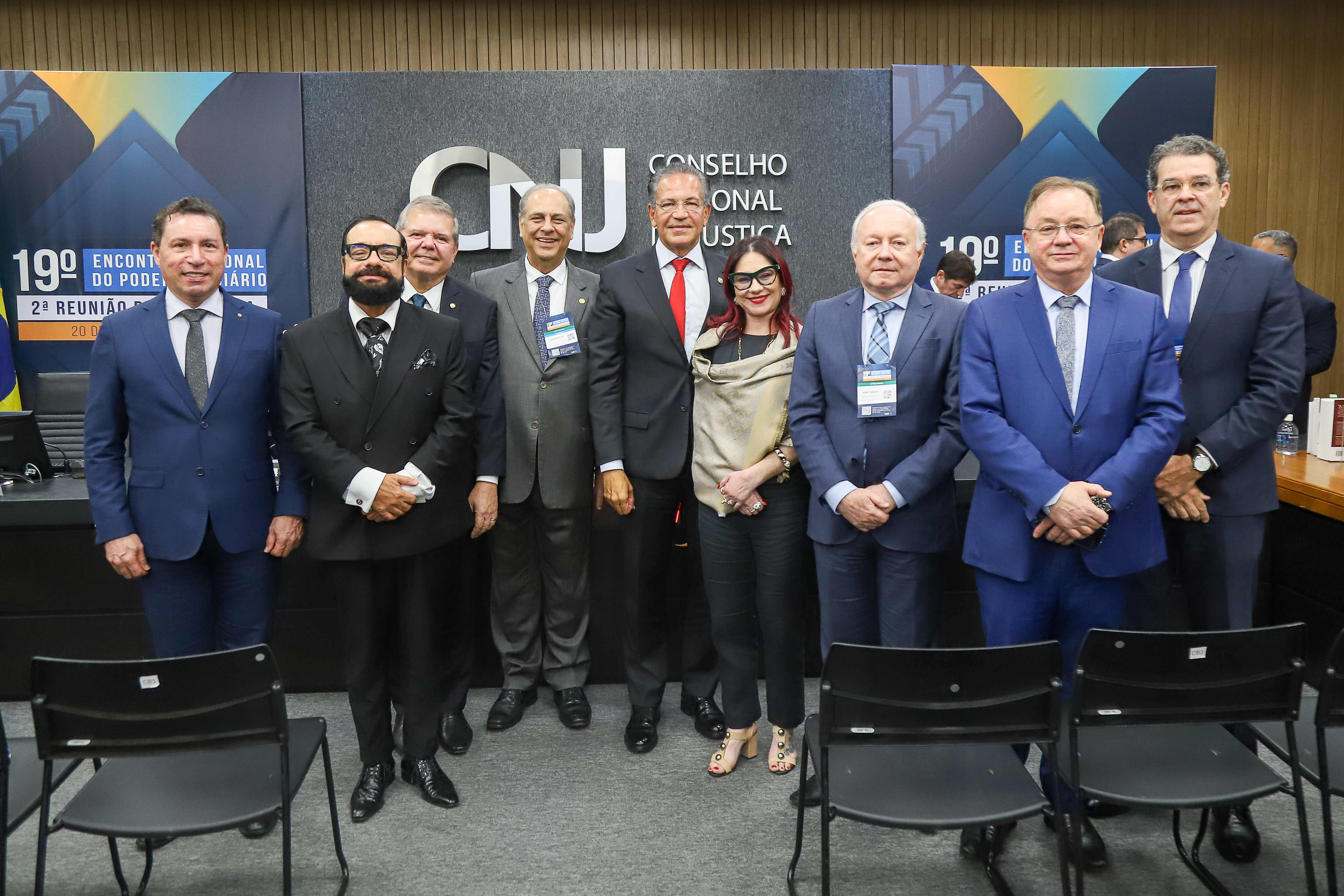 Foto colorida mostra um grupo de autoridades posando para foto oficial diante do painel do Conselho Nacional de Justiça (CNJ), durante o 19º Encontro Nacional do Poder Judiciário. Os participantes estão alinhados em frente ao painel, sorridentes e trajando roupas formais. Entre eles o presidente do TJRR, Desembargador Leonardo Cupello. Foto colorida mostra um grupo de autoridades posando para foto oficial diante do painel do Conselho Nacional de Justiça (CNJ), durante o 19º Encontro Nacional do Poder Judiciário. Os participantes estão alinhados em frente ao painel, sorridentes e trajando roupas formais. Entre eles o presidente do TJRR, Desembargador Leonardo Cupello.