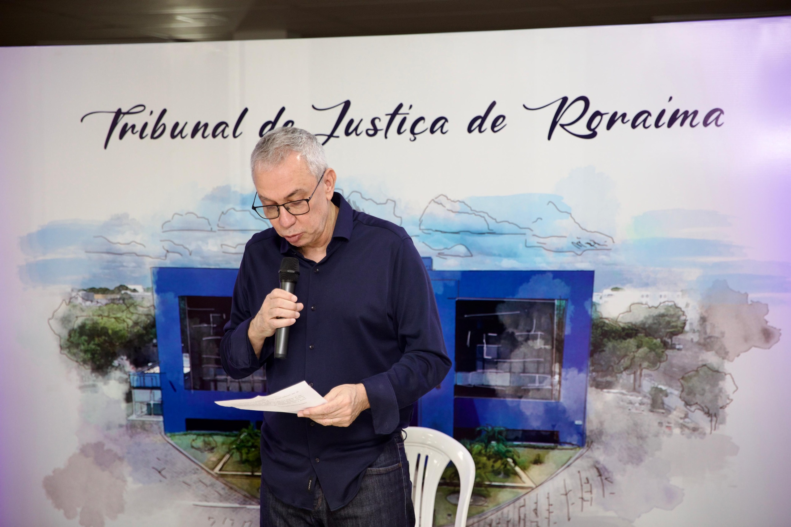 Imagem colorida mostra o supervisor do GMF, desembargador Almiro Padilha durante discurso. Atrás dele está o backdrop com o título “Tribunal de Justiça de Roraima”. 
