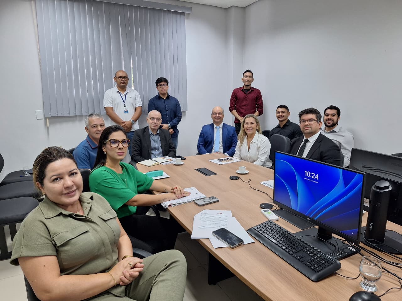 Foto colorida de uma reunião institucional em uma sala de escritório do Tribunal de Justiça de Roraima. Ao redor de uma mesa de madeira clara, estão 12 pessoas, entre homens e mulheres. Foto colorida de uma reunião institucional em uma sala de escritório do Tribunal de Justiça de Roraima. Ao redor de uma mesa de madeira clara, estão 12 pessoas, entre homens e mulheres.