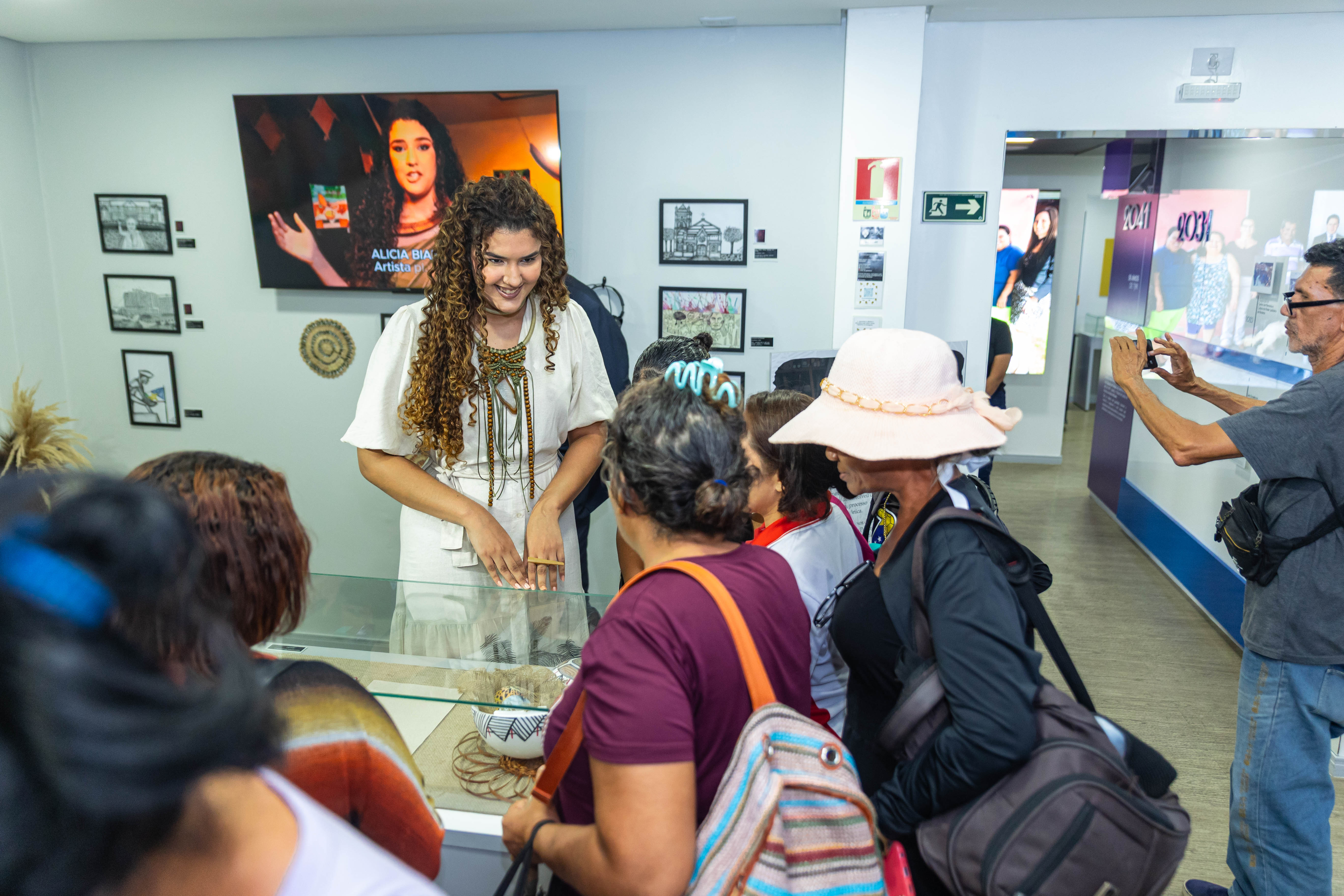 VArtista interagindo com o público em uma exposição sobre seu trabalho ou cultura regional, destacando seu papel como criadora.
