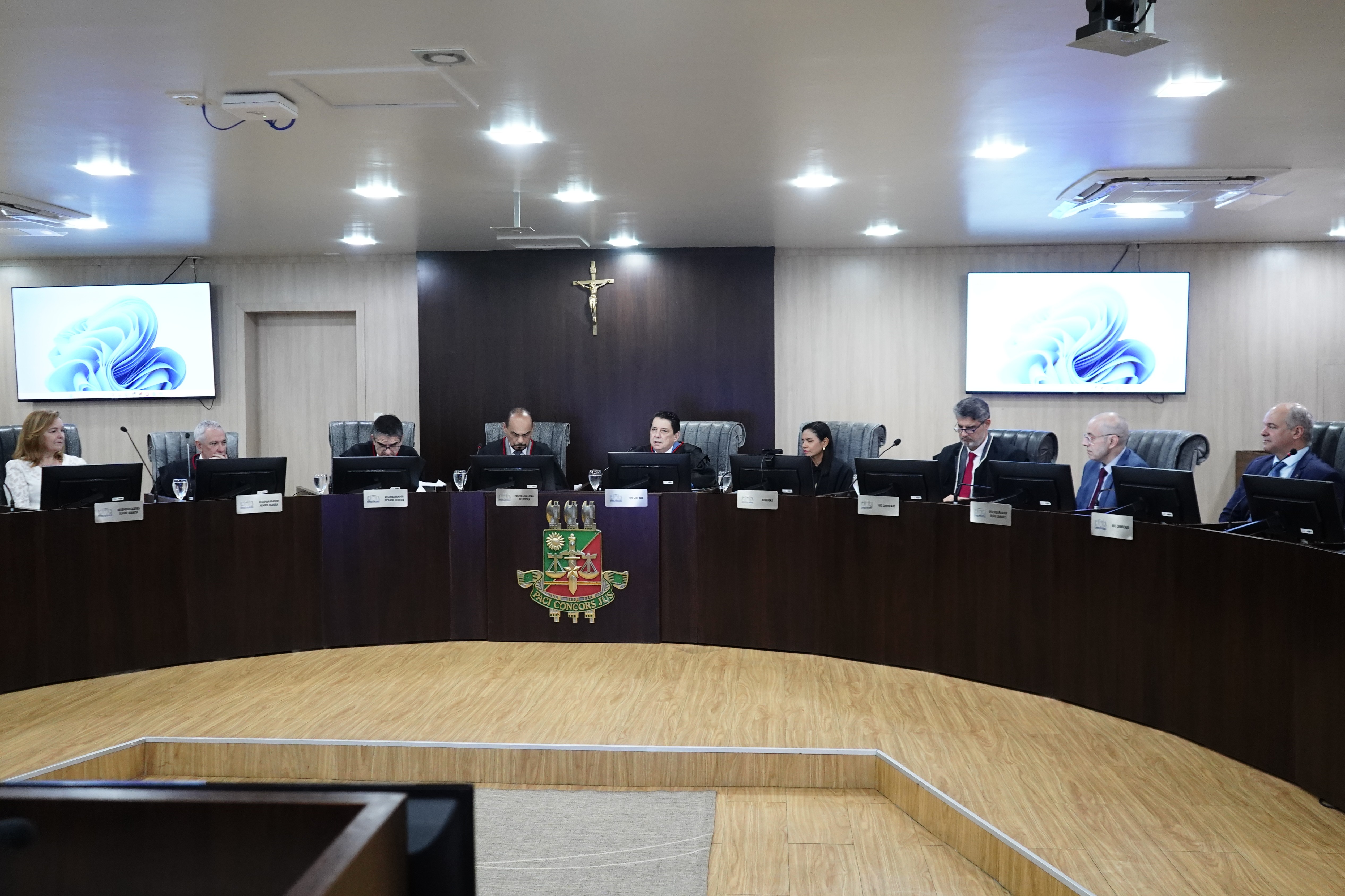 Imagem 2: Imagem colorida mostra nove autoridades do Judiciário roraimense sentados no plenário do Tribunal Pleno do TJRR. Há duas tv 's atrás do plenário. Imagem 2: Imagem colorida mostra nove autoridades do Judiciário roraimense sentados no plenário do Tribunal Pleno do TJRR. Há duas tv 's atrás do plenário.