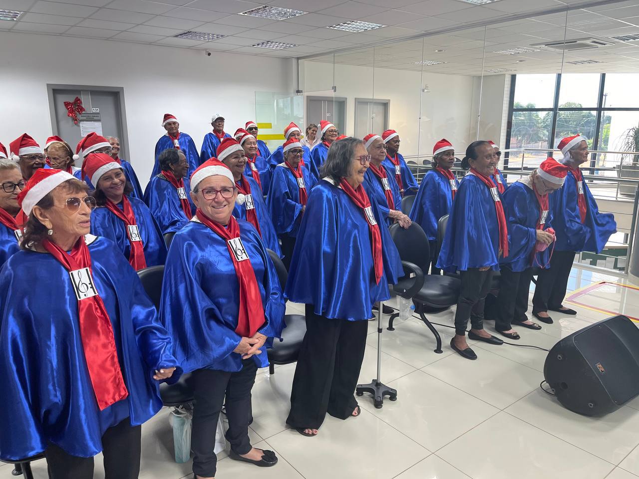 foto colorida do coral de idosos enfileirados e com gorro natalino 