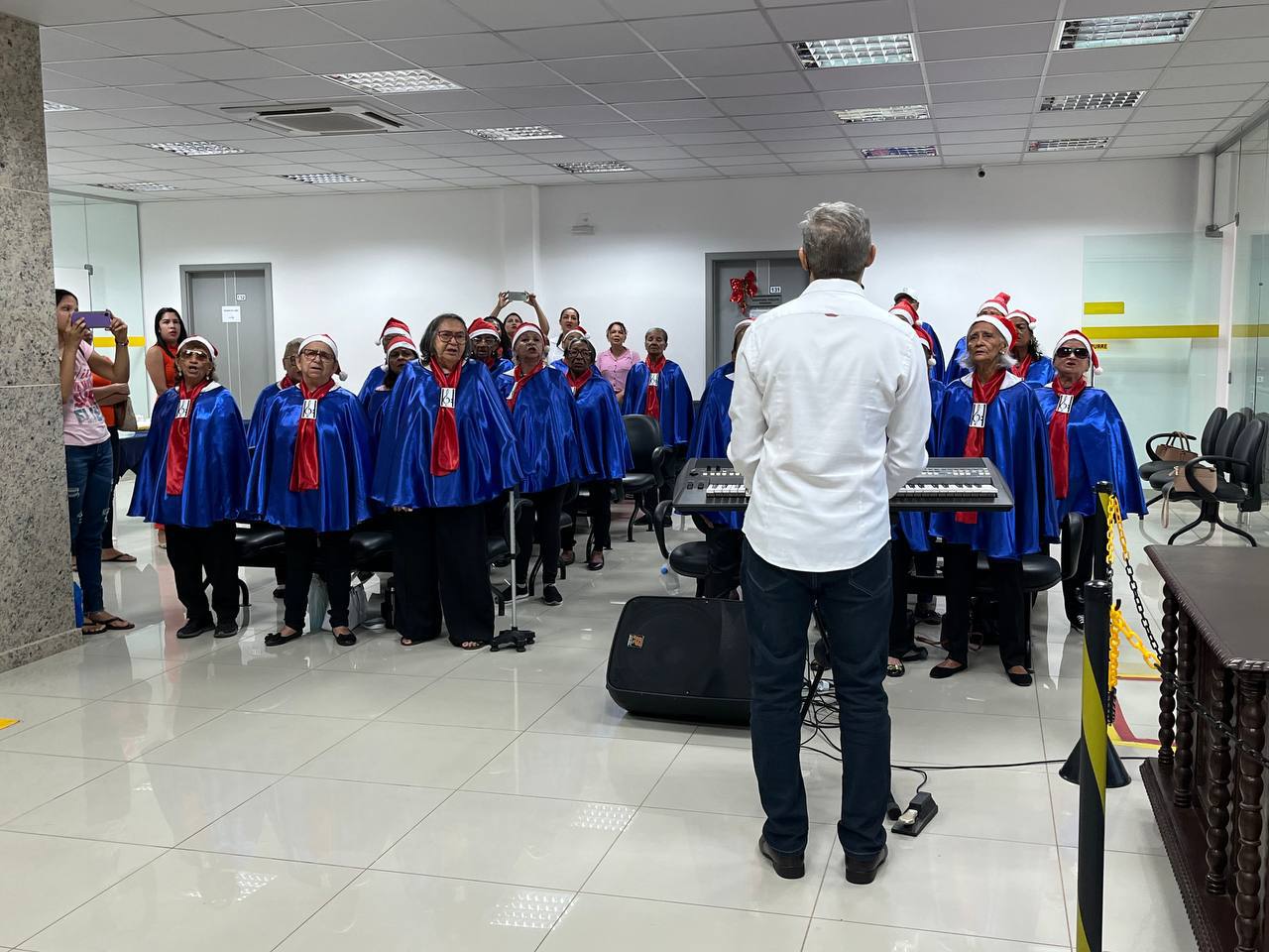 foto colorida do coral de idosos se apresentando dentro de um prédio 