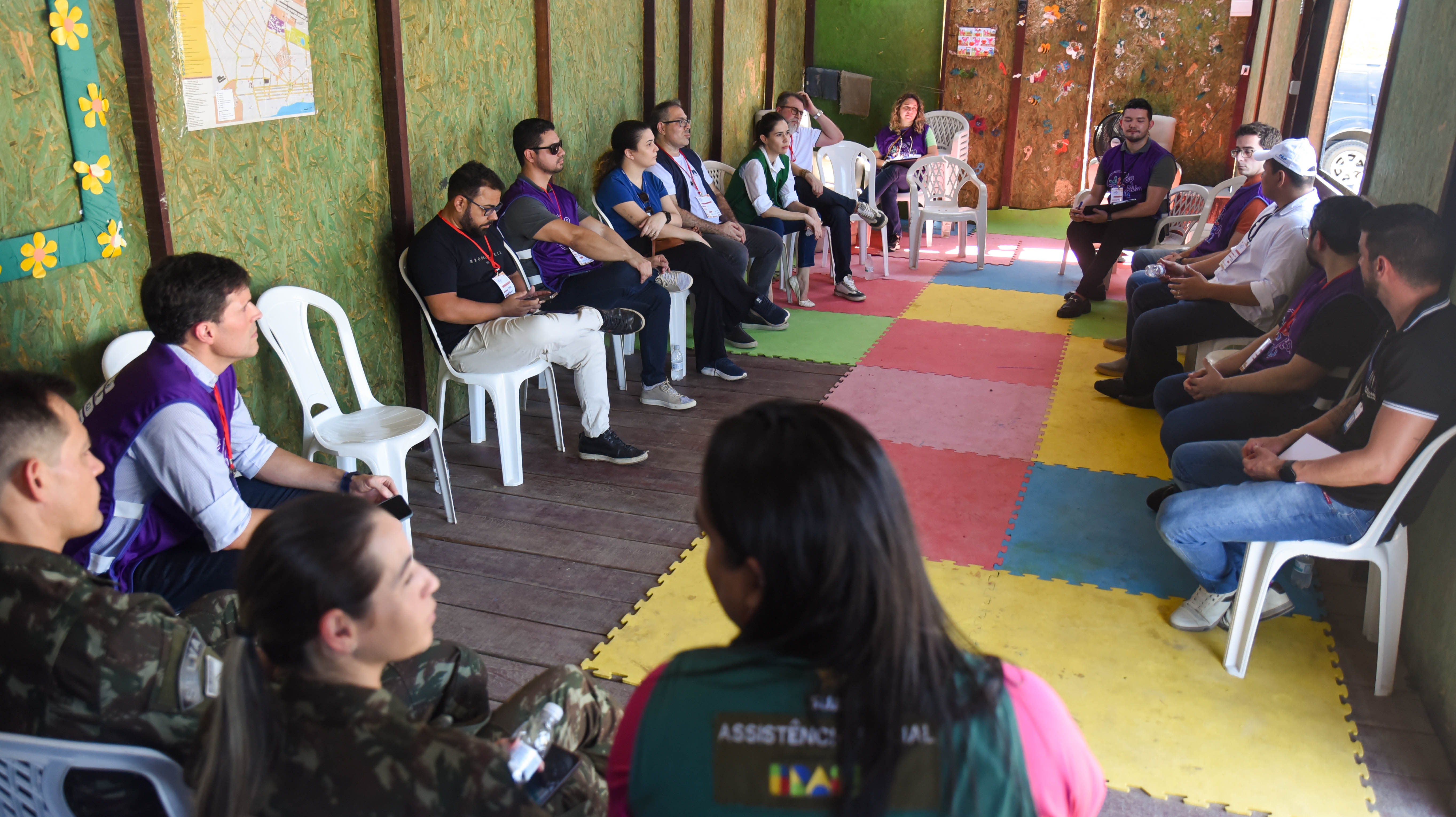 foto colorida de servidores de diversas intuições sentados em circulo no abrigo de Gestão Federal Rondon 5, da Operação Acolhida. 