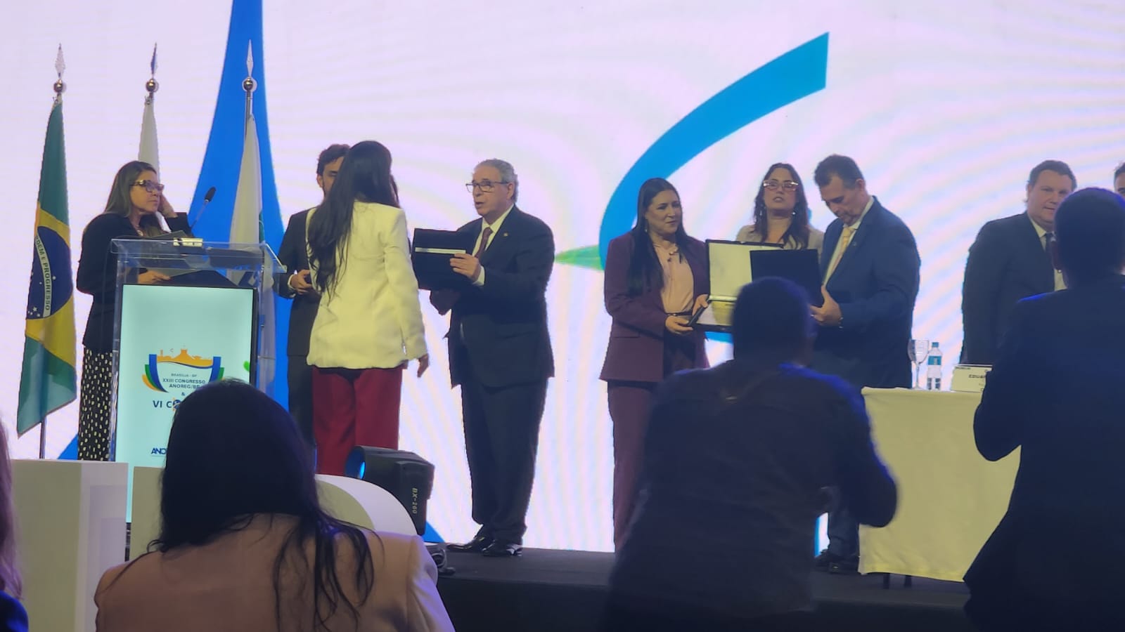  Foto colorida mostra a servidora do TJRR, Luciana Menezes  segurando premiação em homenagem ao desembargador Mozarildo Cavalcanti, durante congresso nacional Anoreg/BR.  