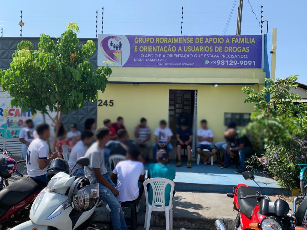 foto colorida onde mostra a parte de fora do nucleo de apoio a usuarios de drogas na foto também há um grupo deles reunidos enfrente ao local