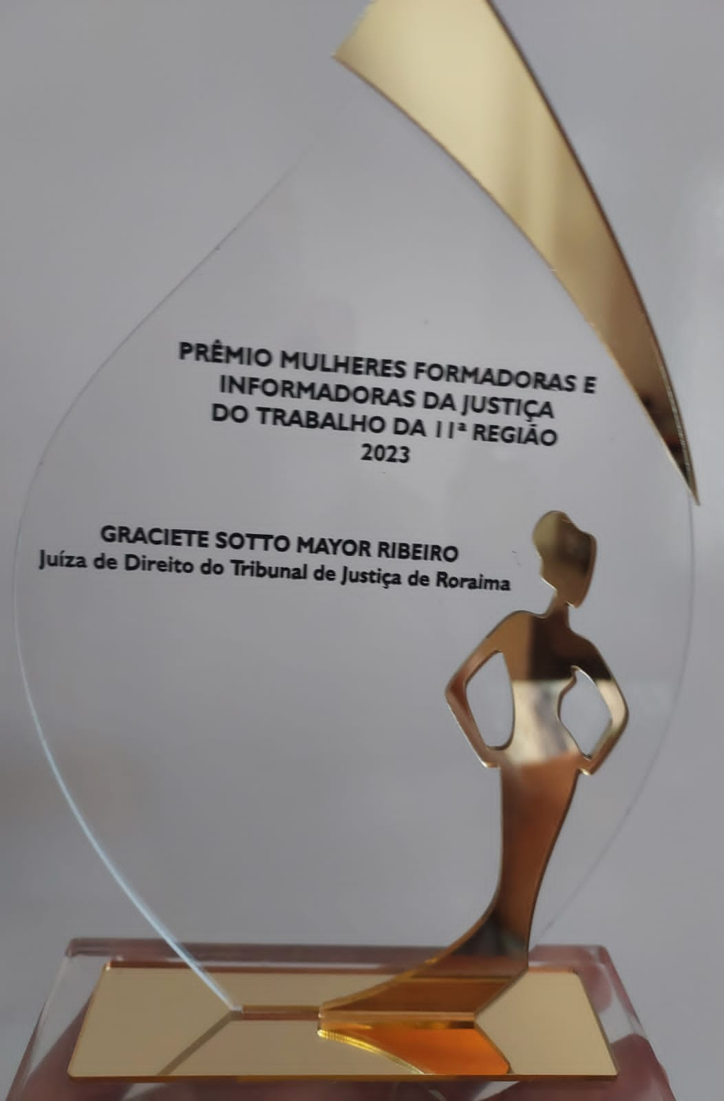  Imagem colorida de um troféu que está escrito "Prêmio Mulheres Formadoras e Informadoras da Justiça do Trabalho da 11ª Região – edição 2023” com o nome da juíza Graciete Sotto Mayor. Abaixo, a frase: Reconhecimento - Juíza Graciete Sotto Mayor recebe prêmio por Contribuição à Justiça do Tabalho e Inclusão Social".