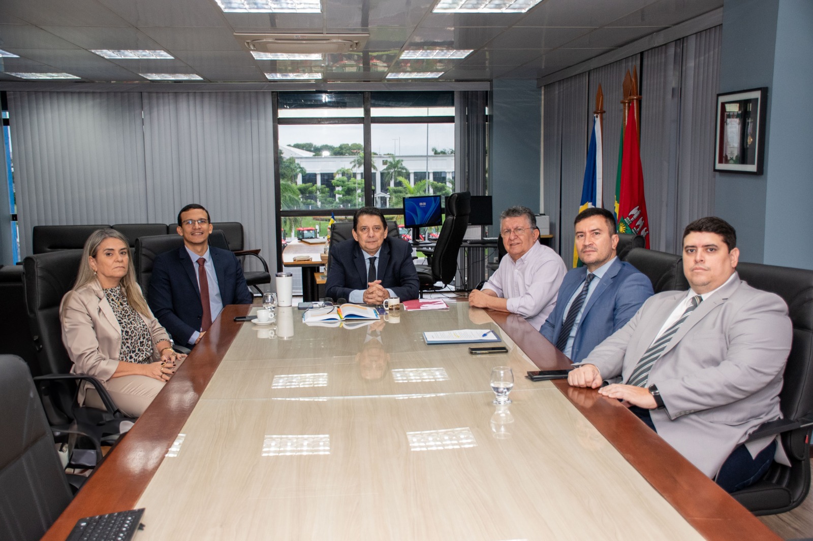 imagem colorida mostra o presidente do TJRR, desembargador Jésus Nascimento, sentado na mesa de reunião da presidência do TJRR, ao lado do chefe da Casa Civil do Poder Executivo, Flamarion Portela, do procurador do estado, Tyrone Mourão, do secretário-geral do TJRR, Henrique Tavares, da coordenadora do Núcleo de Precatórios (NUPREC/TJRR), Valdira Silva, e do assessor coordenador da Presidência, Alexandre Ferreira, durante reunião institucional. 