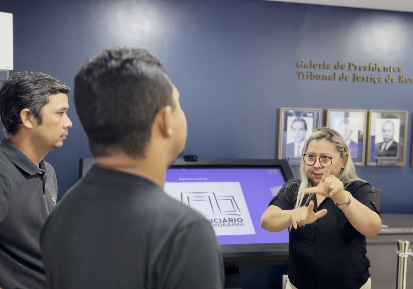 foto colorida de uma interprete fazendo sinais de libras para uma pessoa 