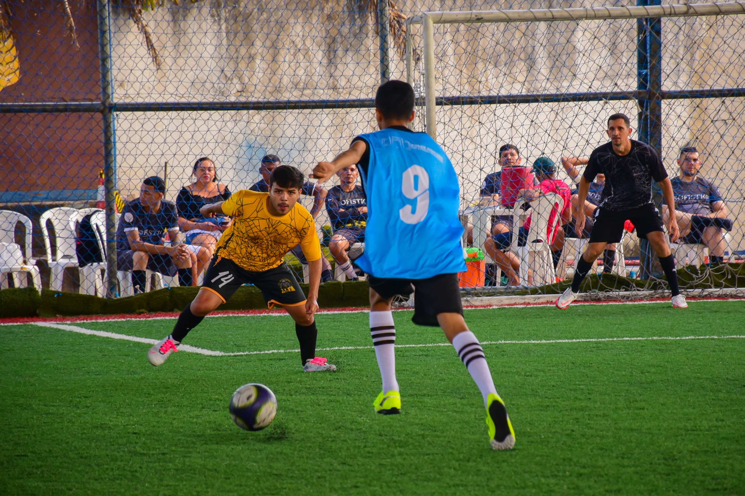 foto colorida em ambiente externo de uma partida de futebol com duas pessoas em um campo de grama