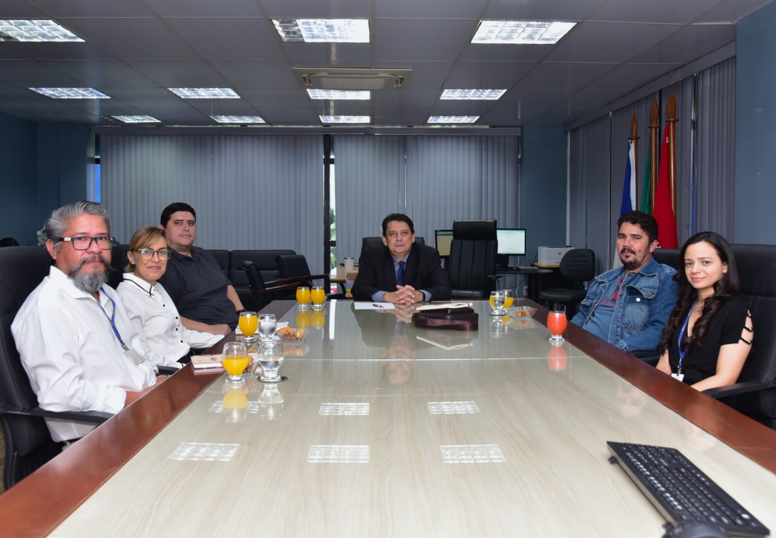 foto colorida de uma reunião do gabinete do presidente do TJRR. Há dois homens e uma mulher sentado ao lado esquerdo da mesa, no meio está o presidente do tjrr e ao lado direito um homem e uma mulher