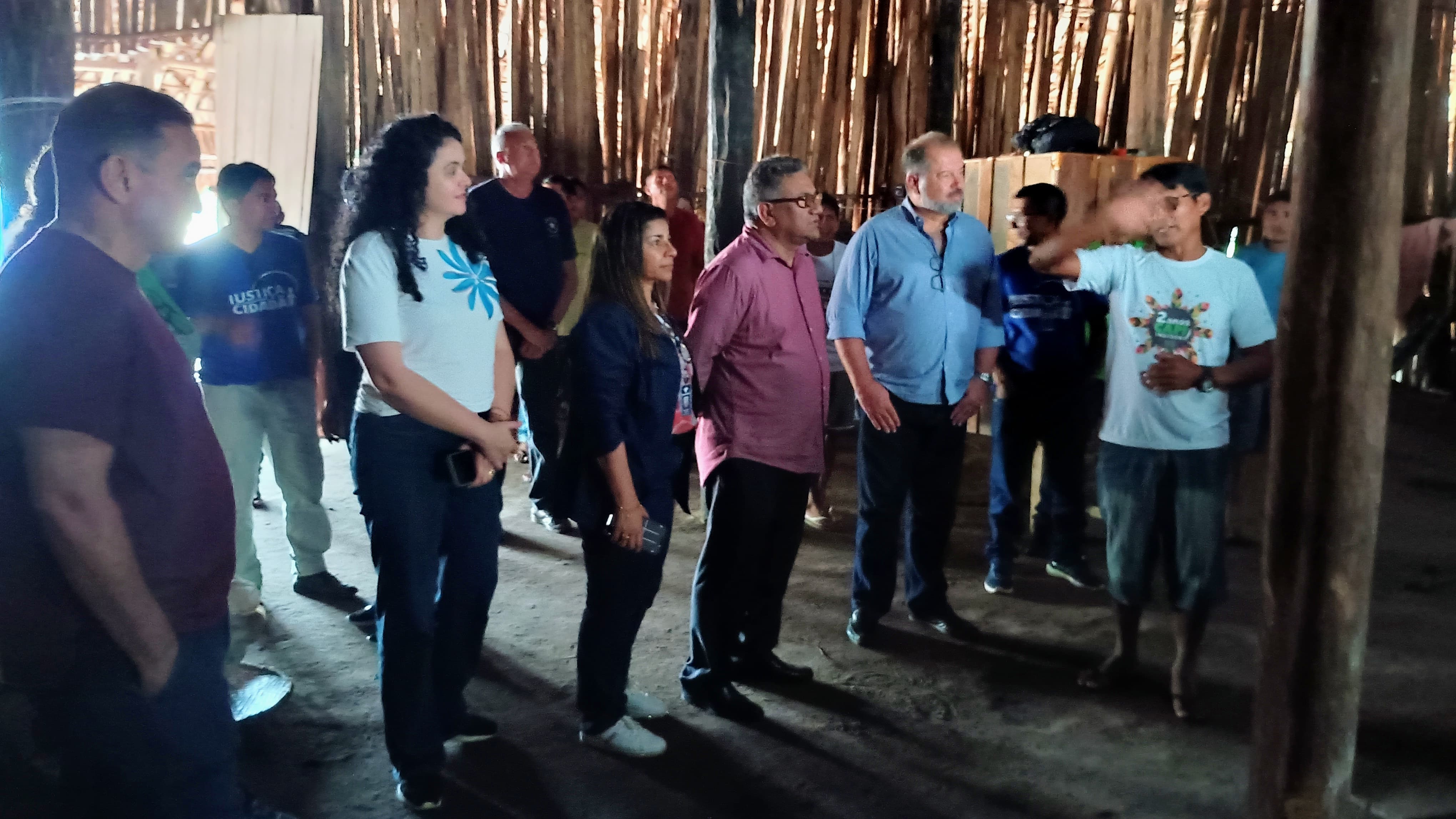 Imagem colorida mostra servidores da Ouvidoria-Geral do Tribunal de Justiça de Roraima interagindo com representantes da Terra Indígena Waimiri-Atroari em parte interna da comunidade.